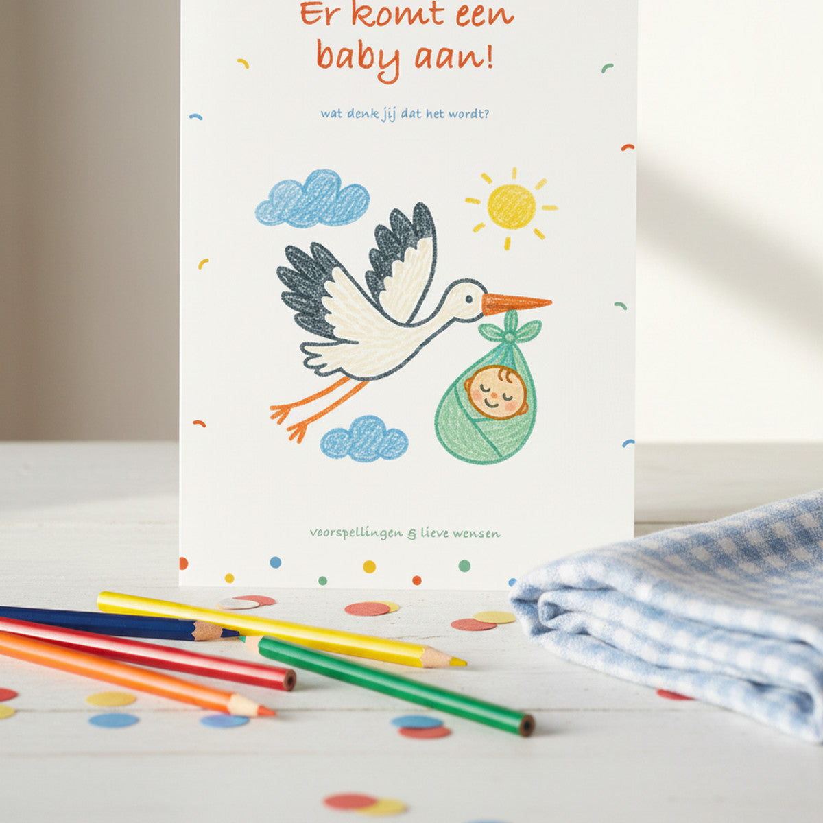 Babyshower invulkaart met ooievaar rechtop tussen kleurpotloden en confetti