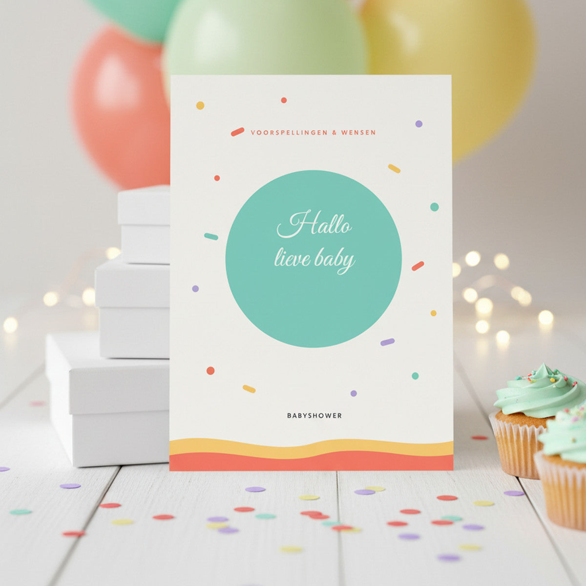 Kleurrijke babyshower invulkaart op een feesttafel met ballonnen, confetti en cupcakes