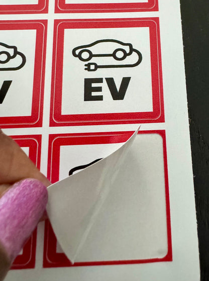 Vierkante EV-laadpaalsticker van 4 x 4 cm wordt van het vel getrokken, met meer stickers eromheen
