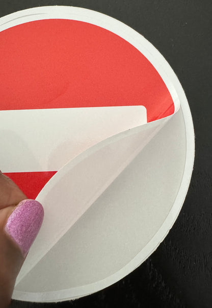 Ronde rood-witte verkeersbordsticker die met de hand van het rugpapier wordt getrokken